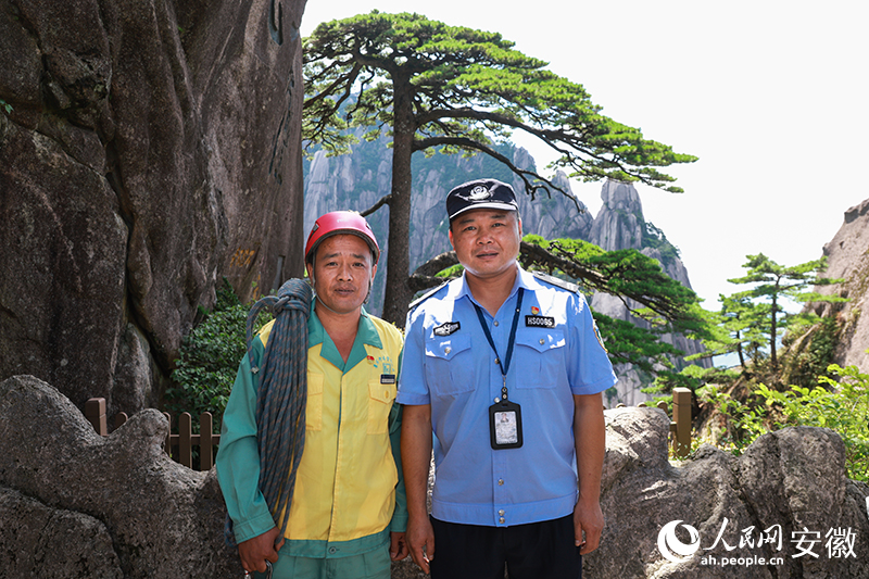 全国道德模范李培生(左)和胡晓春在迎客松前合影。人民网记者 张俊摄